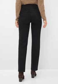 Jeans neri con taglio dritto, dotati di vita alta, tasche posteriori e una texture morbida. Abbinati a stivali con tacco marroni.