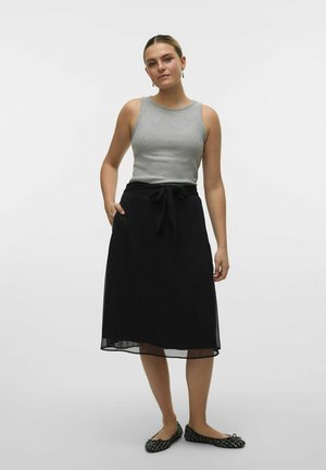 Gray sleeveless top paired with a black skirt featuring a tie waist and pockets; flat black patterned shoes complete the outfit.