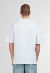 White cotton T-shirt with a relaxed fit, short sleeves, and a crew neck. Simple design, no patterns or accents visible.