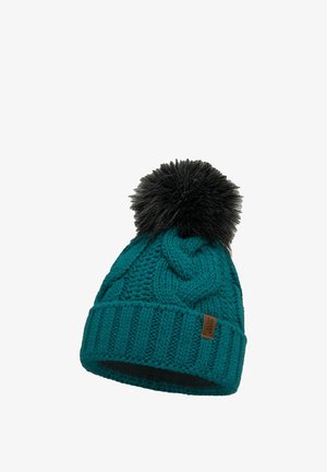 Gorro de punto en color teal con patrón de cable, que presenta un pompón de pelaje sintético negro en la parte superior y una etiqueta de cuero marrón en el borde.