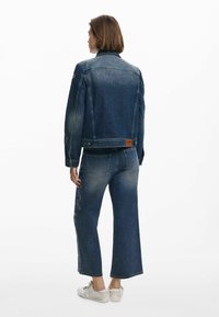 Jeansjacka med en blekt tvätt, med sömdetaljer på ärmarna och en läderetikett. I par med vida jeans och avslappnade skor.