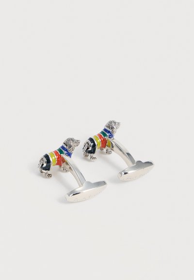 Ασημένια μανικετόκουμπα σε σχήμα ντάξχουντ που φορούν ριγέ πουλόβερ σε μπλε, πράσινο, κίτρινο, πορτοκαλί και κόκκινο χρώμα.