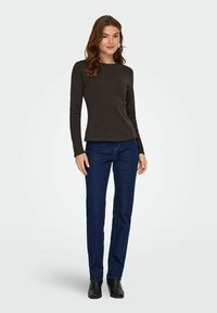 Langsleeve, nauwsluitend donkerbruin top met een ronde halslijn, gecombineerd met een rechte spijkerbroek in het blauw en zwarte enkellaarsjes. Eenvoudige, gladde texturen.