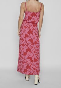 Maxi dress in red with large pink floral patterns. Features thin spaghetti straps and a relaxed fit, made from a soft, lightweight fabric.