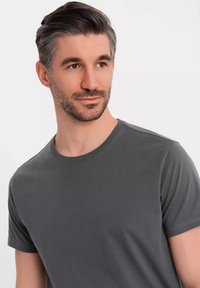 Grå crew-neck t-shirt lavet af glat stof med korte ærmer og en afslappet pasform, med subtile stikninger ved halsudskæringen.