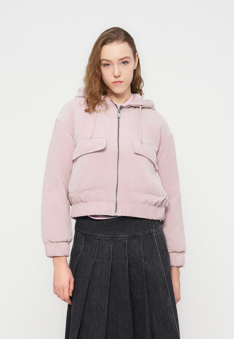 Ροζ κοντό τζάκετ από κορντόι με κουκούλα, φερμουάρ μπροστά και δύο τσέπες στο στήθος. Διαθέτει ελαστικές μανσέτες και τελείωμα, με απαλή υφή.