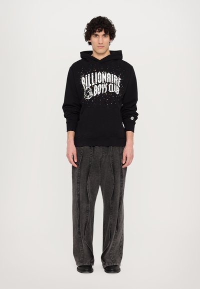 Hoodie noir avec le logo "Billionaire Boys Club", détails éclaboussés multicolores et poche kangourou. Pantalons larges gris foncé, texturés.