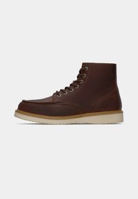 Bottines en cuir marron à lacets avec une semelle en caoutchouc beige, des coutures moc toe et sept paires d'œillets en métal.