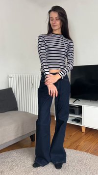 Mustvalgete triibuline pika varrukaga särk, mida on ühendatud tumeliste siniste laiade säärega teksadega. Riietusel on sooniline tekstuur ja vormitud vöökoht.