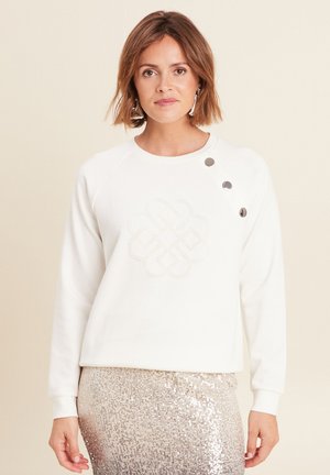 Witte sweatshirt met een getextureerd, geborduurd knoopontwerp op de voorkant, met drie zilveren knoopaccenten op de schouder.
