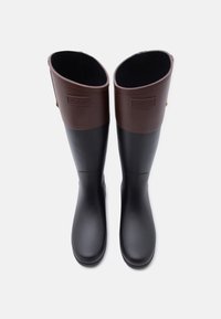 Ζευγάρι μαύρες και σκούρες καφέ λαστιχένιες μπότες βροχής μέχρι το γόνατο με ανάγλυφο το λογότυπο Hunter στον κορμό, φωτογραφημένες από πάνω σε λευκό φόντο.