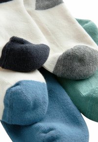 Drei Paar Socken in verschiedenen Farben: Creme, Marineblau, Grau, Hellblau und Mintgrün. Besonders auffällig sind die kontrastierenden Zehenfarben und die gerippte Textur.