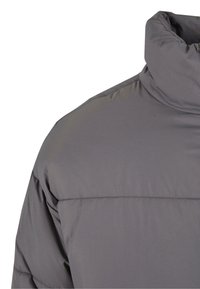 Graue Steppjacke mit hohem Kragen, glattem Stoff mit angenehmer Textur und horizontalen Steppnähten über den Schultern.