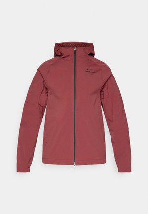 Czerwona, lekka kurtka z pełnym zamkiem błyskawicznym z przodu, regulowanym kapturem i wyhaftowanym logo na górnej lewej stronie. Lekko teksturowana tkanina.