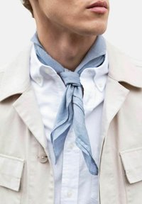 Lyseblå tørklæde lavet af letvægtsstof, bundet løst om halsen, parret med en hvid skjorte med knapper og en beige yderjakke.