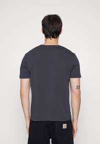 Námorně modré tričko s krátkým rukávem vyrobené z bavlny, s kulatým výstřihem a rovný lem. Měkká textura bez viditelných vzorů nebo akcentů.