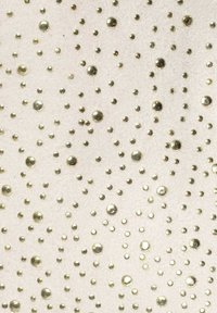 Texturovaná tkanina se světlým pozadím a různě velkými metalickými zlatými tečkami, které vytvářejí rozptýlený vzor po celé ploše.