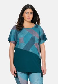 Top de tallas grandes con mangas cortas, que presenta un fondo turquesa y patrones geométricos en tonos de turquesa, rosa y gris. Tejido suave y transpirable.