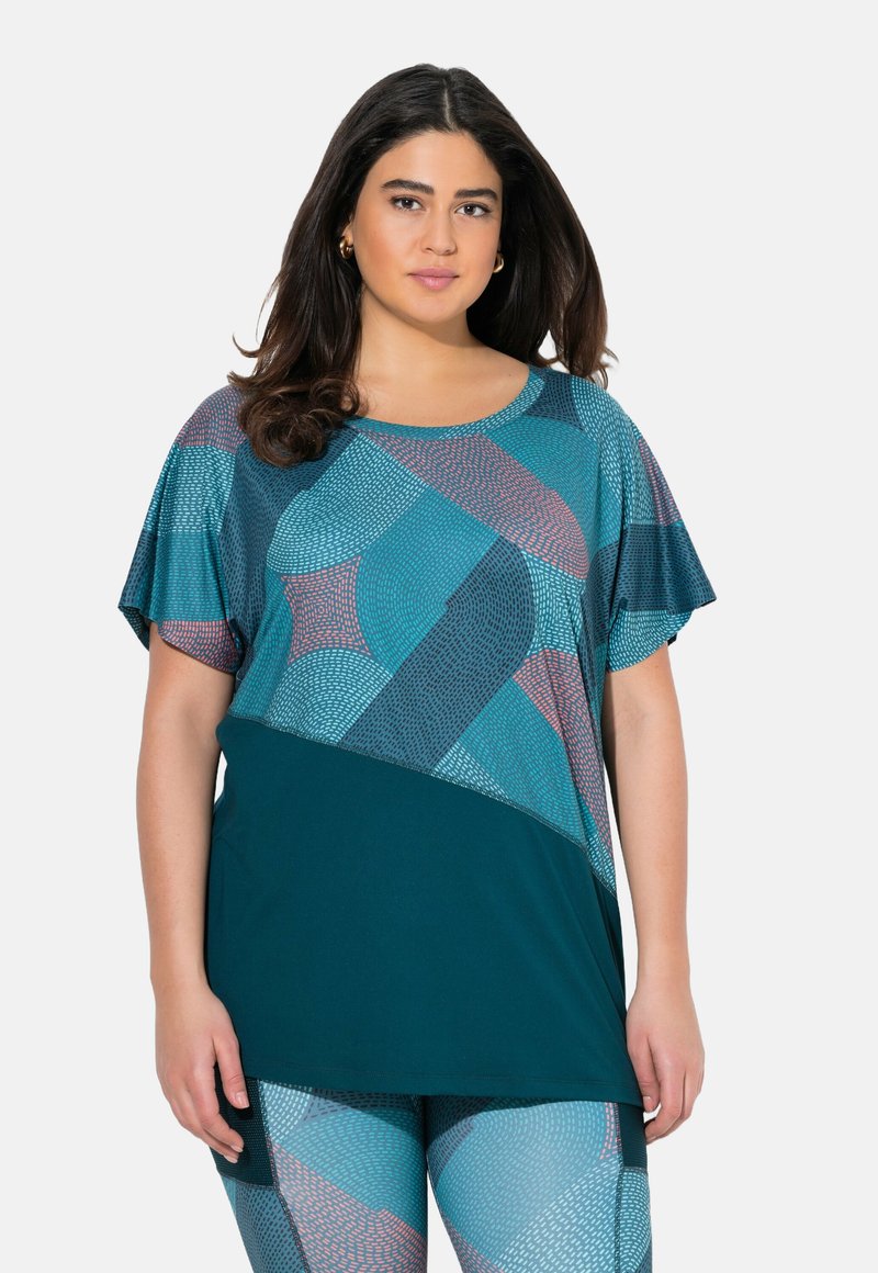 Top de tallas grandes con mangas cortas, que presenta un fondo turquesa y patrones geométricos en tonos de turquesa, rosa y gris. Tejido suave y transpirable.