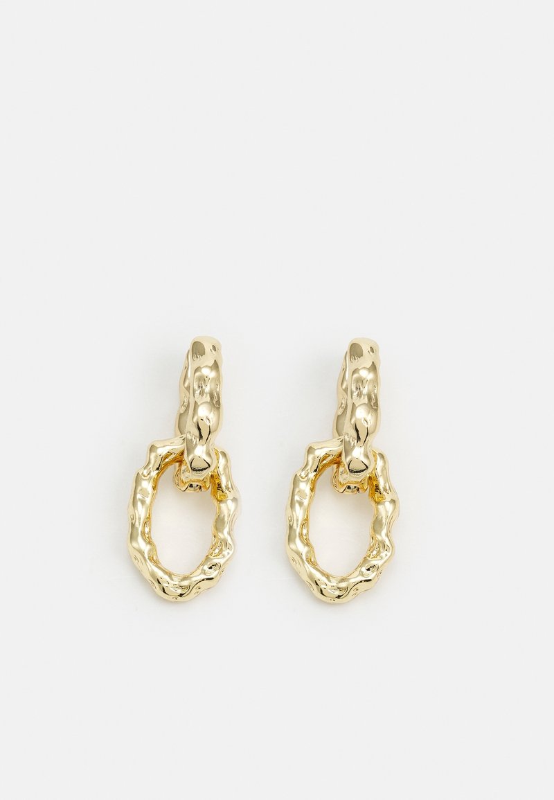Paire de boucles d'oreilles créoles dorées brillantes avec des formes circulaires texturées et irrégulières sur un fond clair uni.