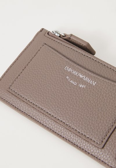Brun strukturert lær kortholder med glidelåslomme, med preget logo "EMPORIO ARMANI" og glatte detaljer.