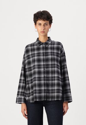 Black and gray plaid oversized shirt with a button-down collar, featuring a relaxed fit and frayed hem. Made from a soft fabric.