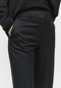 Zwarte op maat gemaakte broek met een gladde textuur, voorzien van zijzakken en een subtiele tailleband, ontworpen voor een getailleerde silhouet.