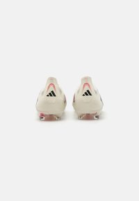 White soccer cleats with black accents and pink details, featuring a smooth texture, low-top design, and transparent studs at the base.