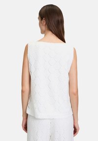 Biała bezrękawnik o teksturowanym wzorze liści, okrągłym dekolcie i luźnym kroju, z prostym wykończeniem i warstwowym fasonem.