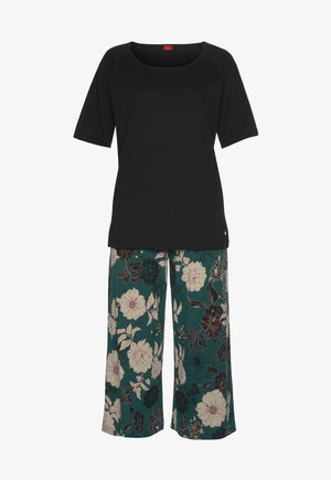 Black short-sleeve top with a square neckline paired with teal floral wide-leg pants featuring large white and black flowers.