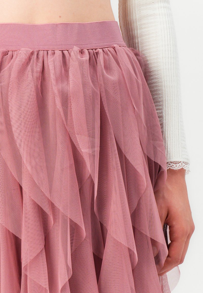 Helle rosa Tüllrock mit geschichteten Rüschen und elastischem Taillenbund. Transparente Textur mit einem sanften, fließenden Erscheinungsbild.