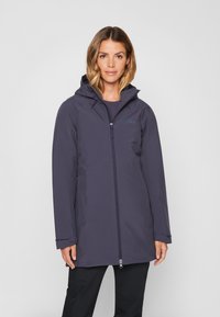 Giacca blu navy impermeabile con cappuccio, chiusura con zip e polsini regolabili. Tessuto liscio con cuciture ridotte al minimo e silhouette aderente.