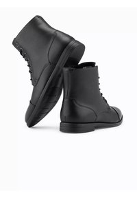 Botas de tobillo de cuero negro con un acabado texturizado, con puntera redonda, cordones en la parte delantera y una suela plana de goma para mayor tracción.