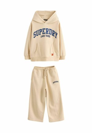 Beige hoodie med blå "SUPERDRY LAKE TAHOE" tryck, framficka och matchande sweatpants med sidofickor och logotyp. Mjukt material, avslappnad passform.