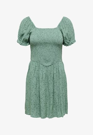 Zielona sukienka w kwiatowy wzór z kwadratowym dekoltem, krótkimi bufkami oraz marszczonym górnym częścią. Posiada rozkloszowaną spódnicę i lekki materiał.