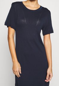Granatowa dzianinowa sukienka z krótkimi rękawami, z okrągłym dekoltem i subtelnymi teksturowanymi akcentami na ramionach i przodzie.