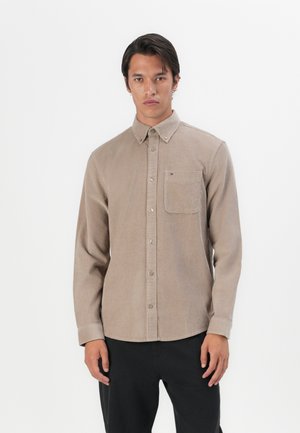Brown button-up shirt made of textured fabric with a chest pocket, featuring a button-down collar and subtle branding on the pocket.