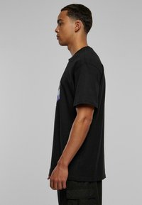 Sort bomulds t-shirt med korte ærmer og rund hals, der har et grafisk design på forsiden. Glat tekstur, afslappet pasform.
