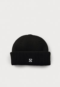 Zwarte gebreide beanie met een geribbelde textuur, voorzien van een opgerolde omslag en een klein wit logo aan de voorkant.