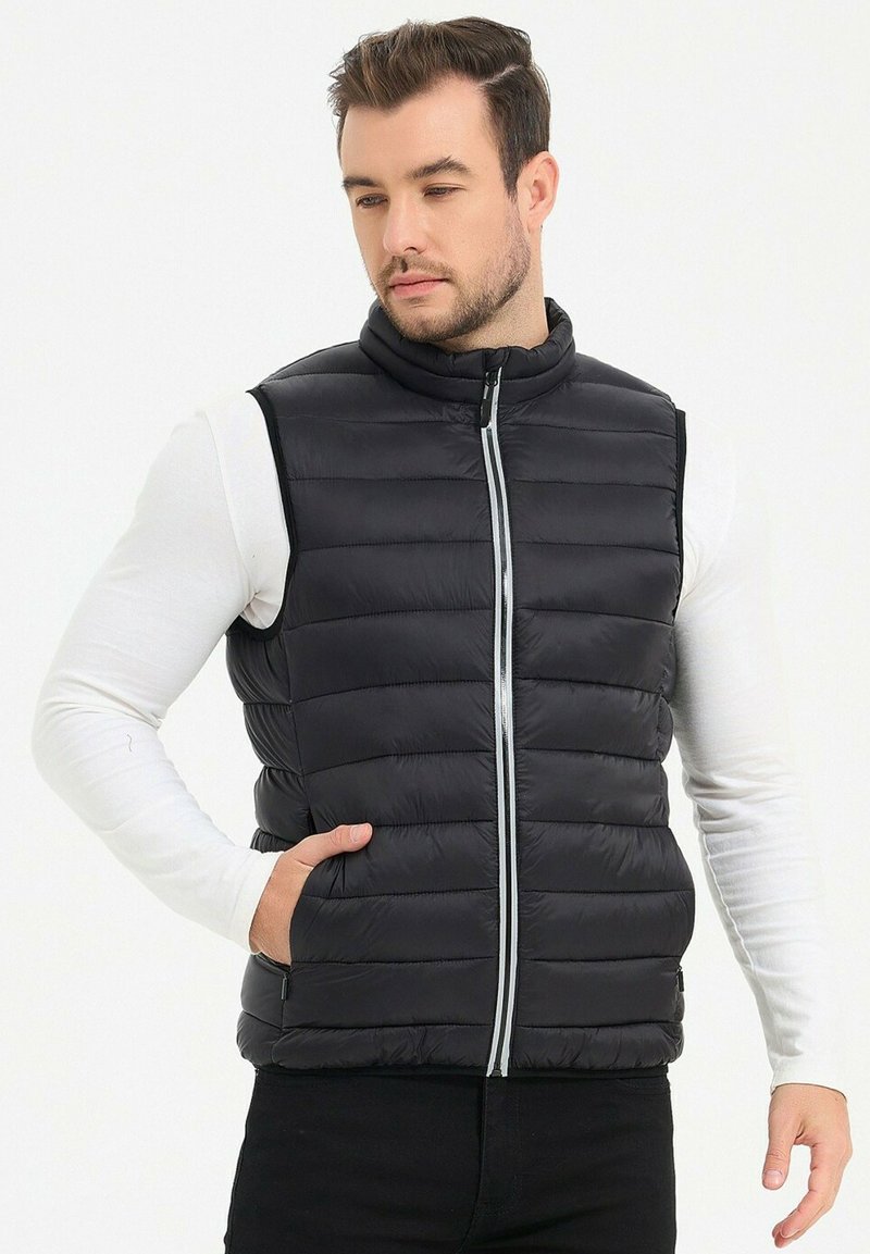 Gilet en doudoune noire avec un col haut, fermeture éclair à l'avant et poches latérales ; présente une texture matelassée et un design élégant et ajusté.