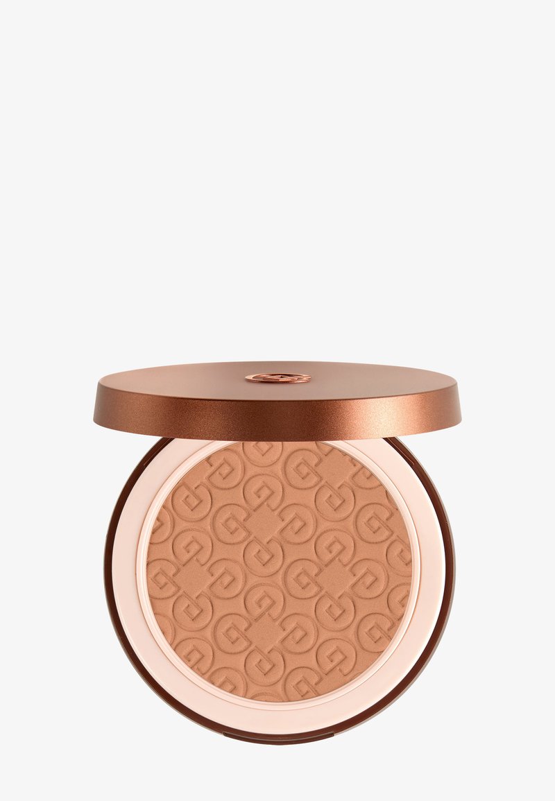 Bronzer compact avec motif géométrique en relief et couvercle métallique rose doré partiellement ouvert sur fond blanc.