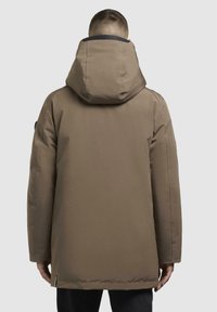 Brun isoleret parka med en stor hætte, glat tekstur og en afslappet pasform. Indeholder en subtil logoaccent nær sømmen.