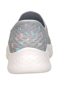 Grijze sportieve schoen met een textuurstof bovenwerk, met een bloemenpatroon in roze, blauw en groen, en een witte rubberen zool.