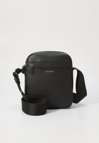 Borsa a tracolla in pelle nera con finitura texturizzata, forma rettangolare, cerniera superiore e tracolla in tessuto regolabile. Presenta dettaglio con logo in rilievo.