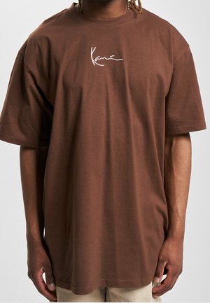 T-shirt en coton marron à coupe décontractée, avec manches courtes et signature brodée blanche sur la poitrine.