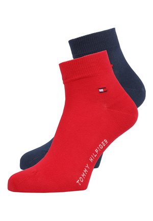 Zwei Paar Knöchelsocken: eines in einfarbigem Rot mit einem Tommy Hilfiger-Logo und eines in einfarbigem Navyblau, beide an den Bündchen verstärkt.