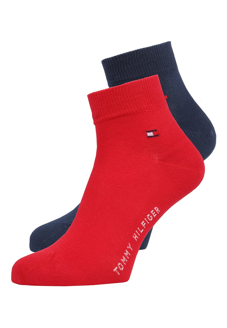 Deux paires de chaussettes de cheville : l'une en rouge uni avec un logo Tommy Hilfiger, et l'autre en bleu marine uni, toutes deux renforcées au niveau des poignets.