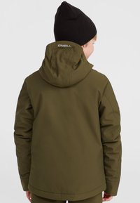 Veste isolante vert olive avec capuche, présentant un design simple et des accents cousus. Logo au col arrière. Texture douce.