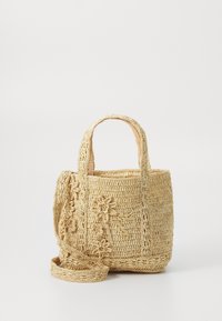 Pletená slaměná kabelka světle béžové barvy se dvěma pevným uchy, květinovými vzory po stranách a nastavitelným ramenním popruhem.