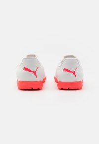 Scarpe sportive Puma bianche con suola rosa brillante. Presentano un logo metallico e una parte superiore testurizzata per una maggiore aderenza e comfort.